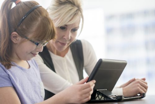 A young woman with visual impairments is getting help from a tutor on her schoolwork and homework.